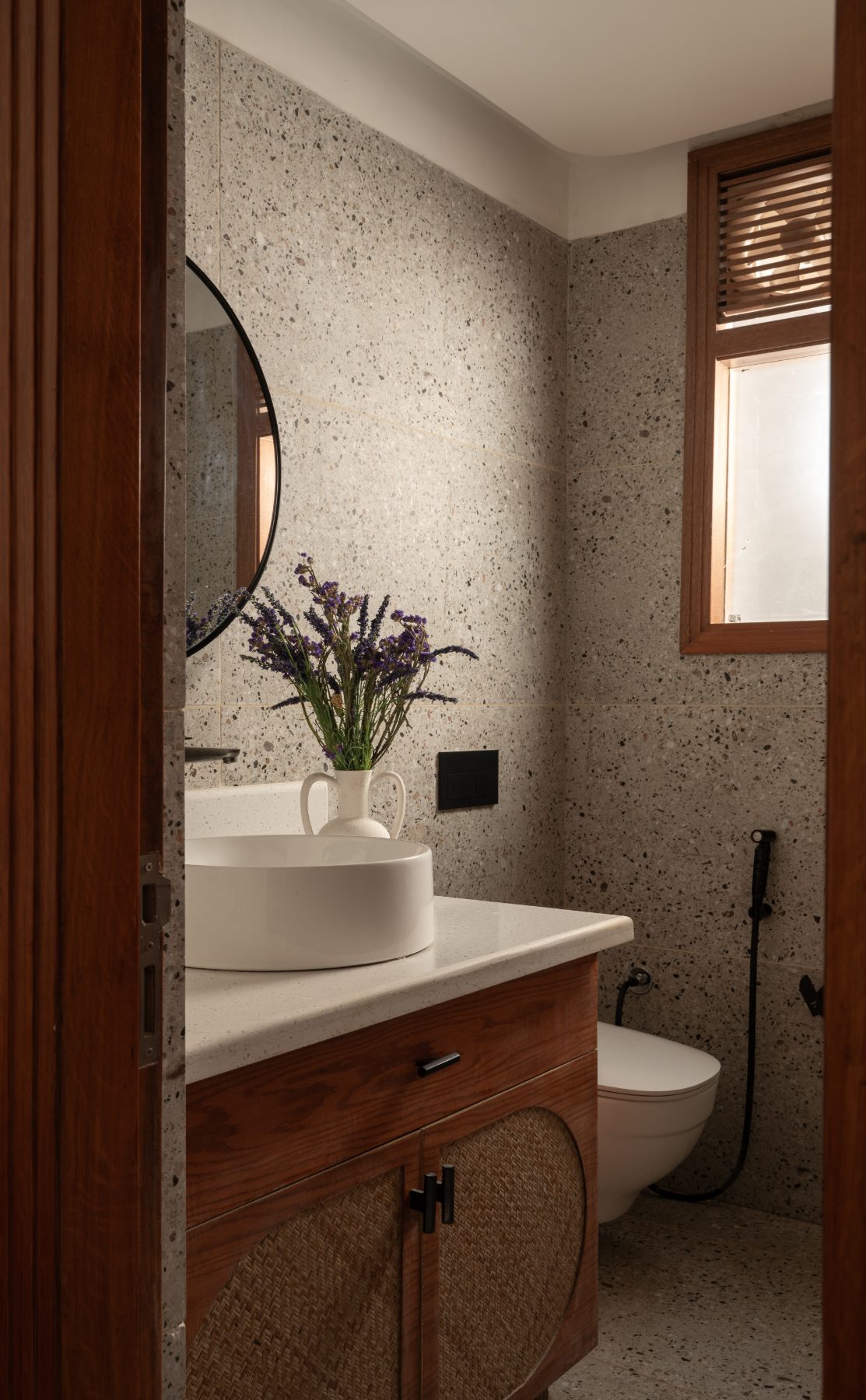 Washroom in terrazzo with a round black mirror