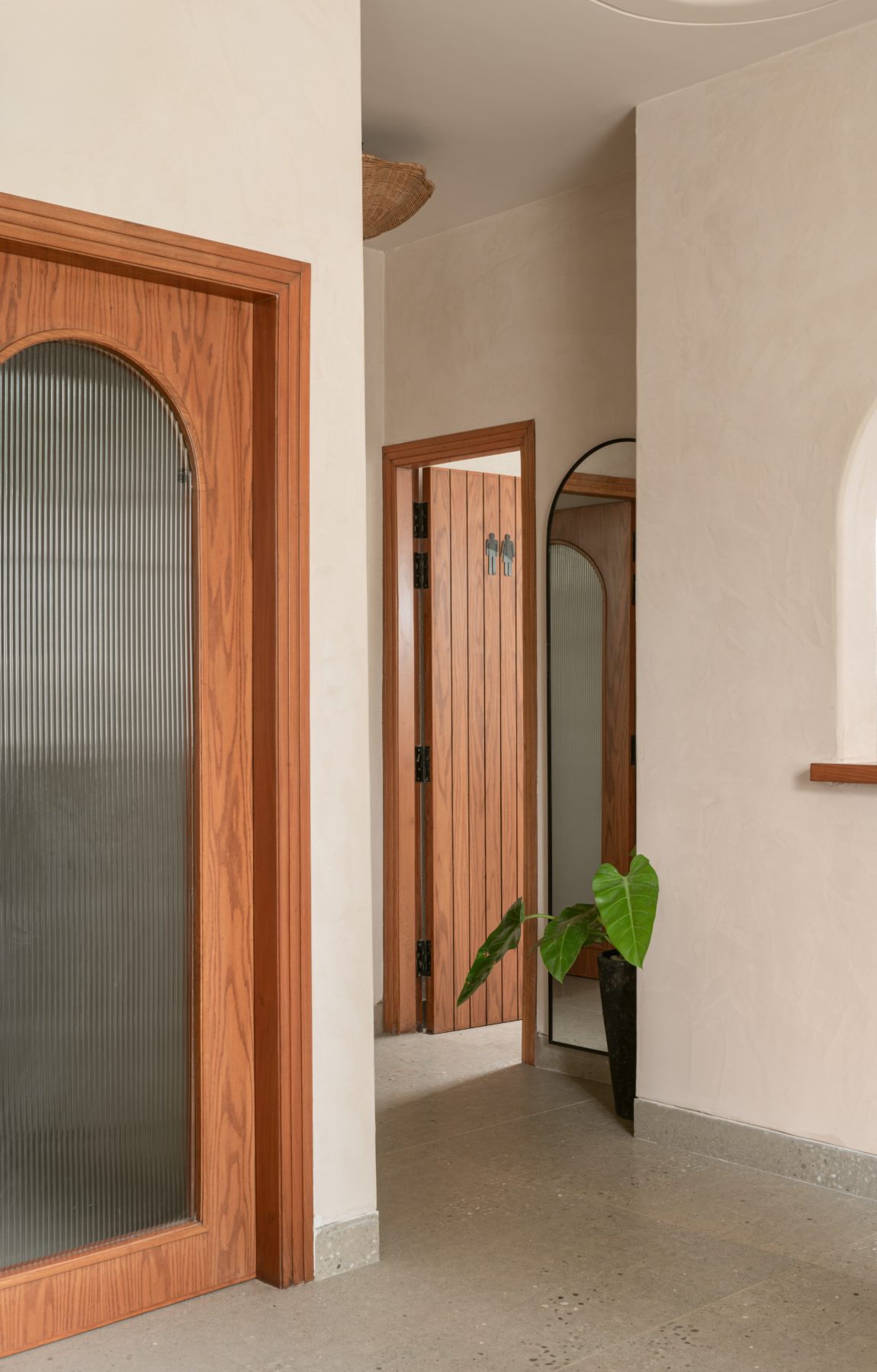 Hallway with reeded-glass doors and a leaning arch mirror