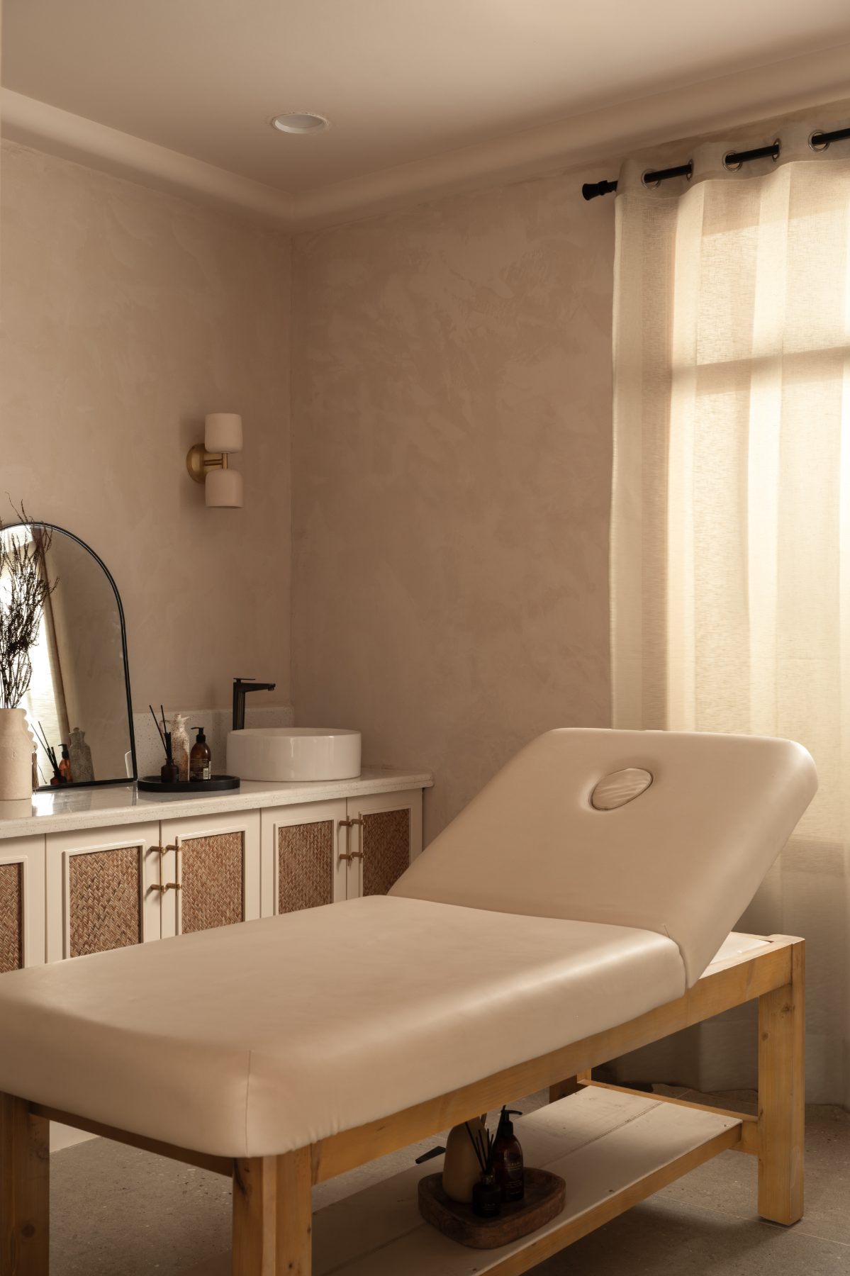 Treatment room with facial bed and arched mirror