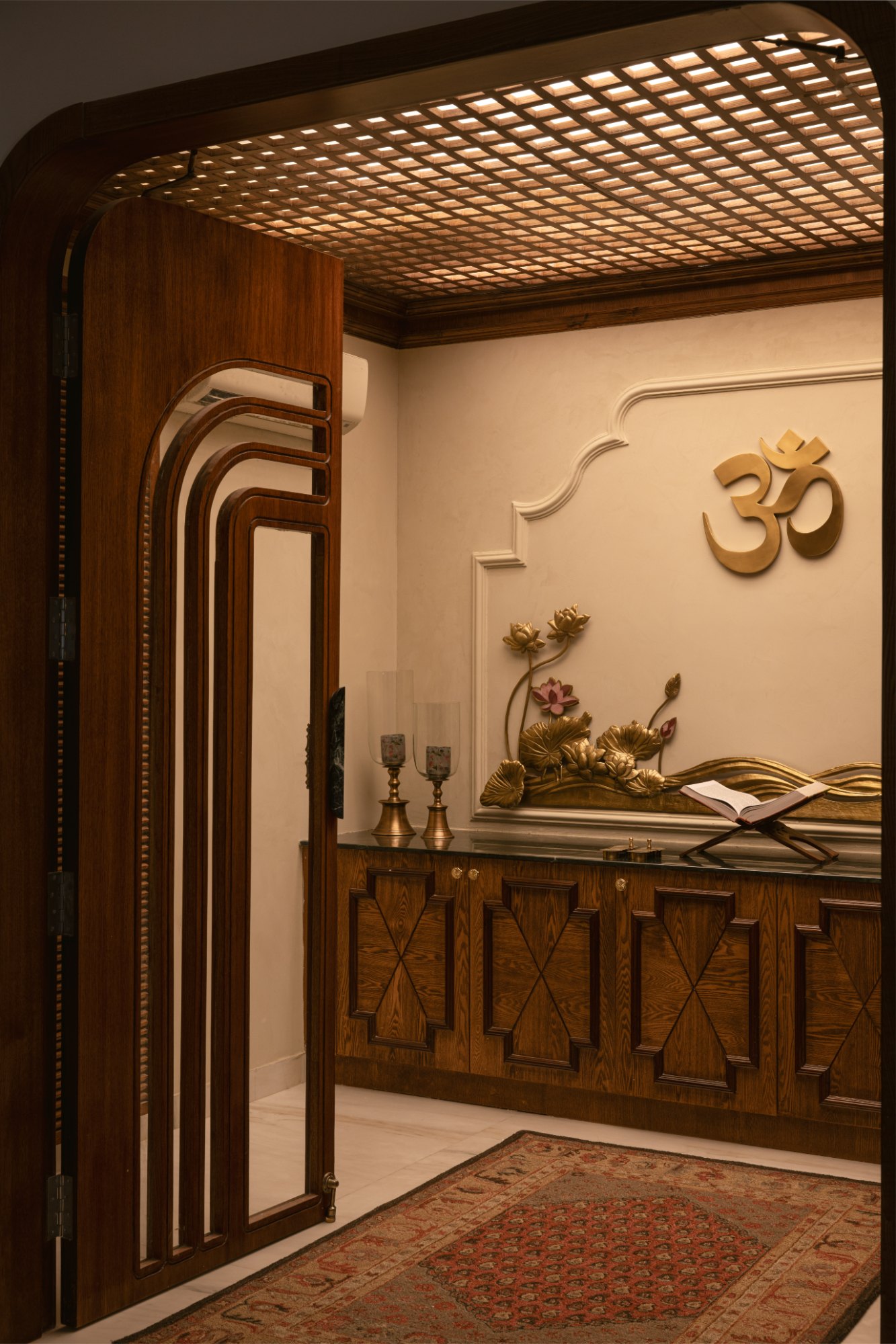 Pooja room with a jaali ceiling, layered arched door and gilded lotus relief