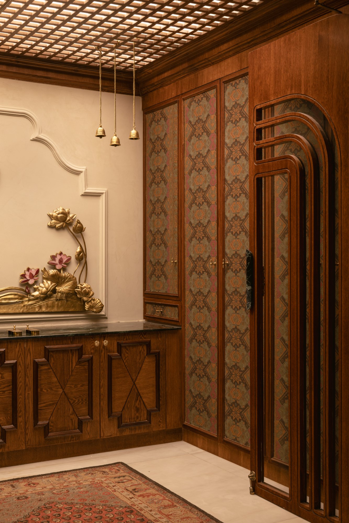 Detail of the pooja room — brocade panelled joinery, brass bells and lotus relief