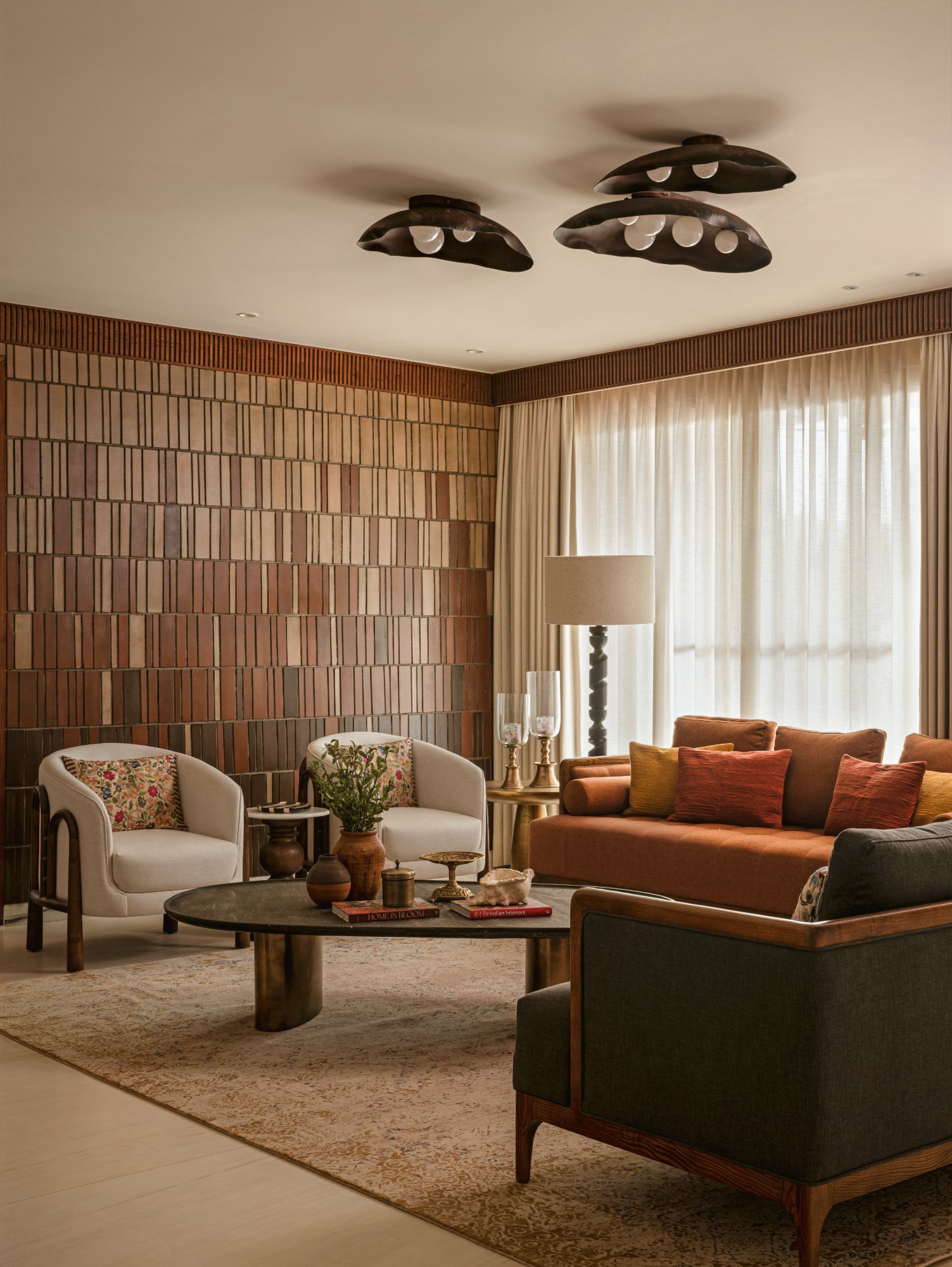 Living room wall of handmade terracotta tile with cream armchairs