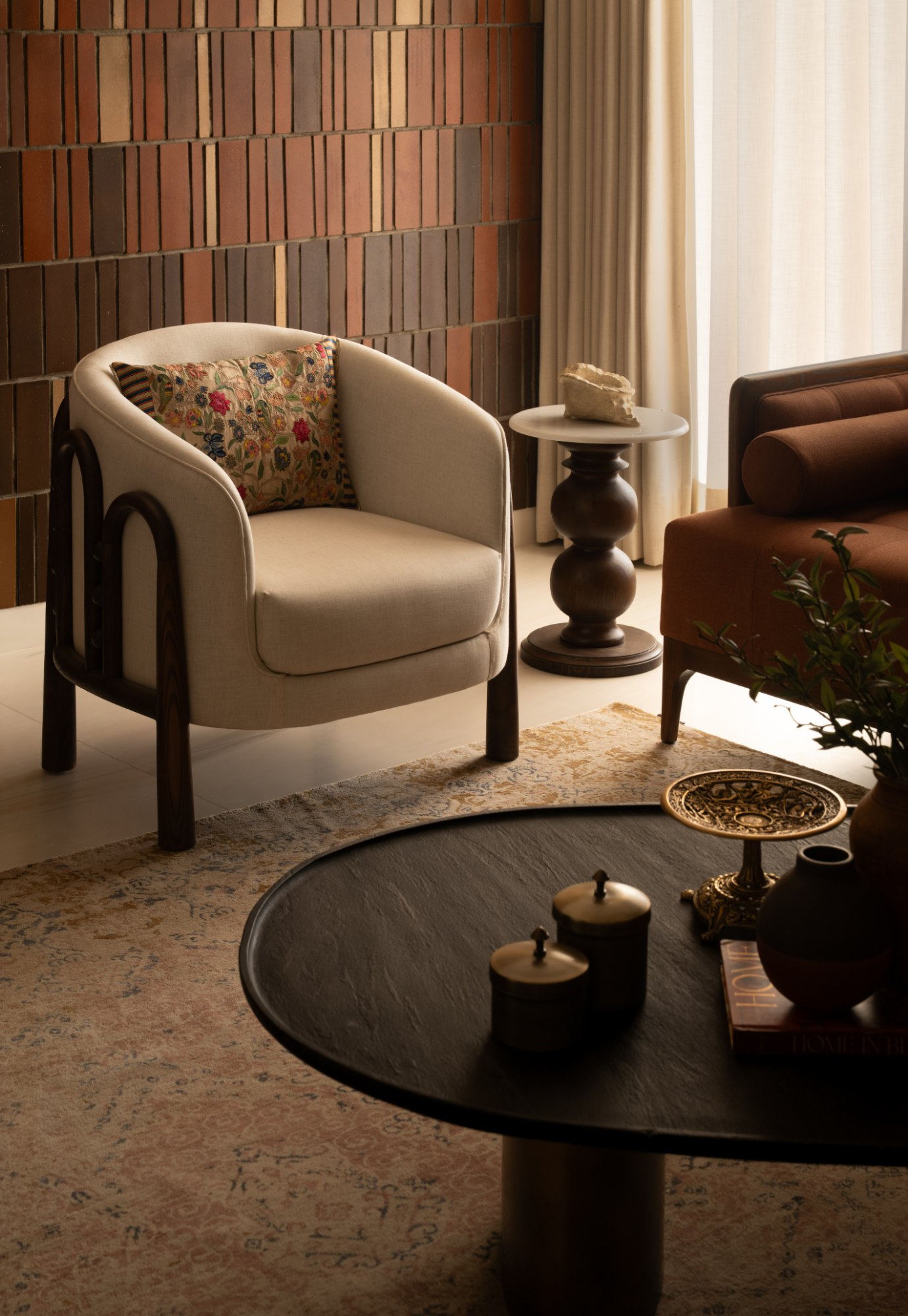 Detail of an armchair, turned side table and black stone coffee table