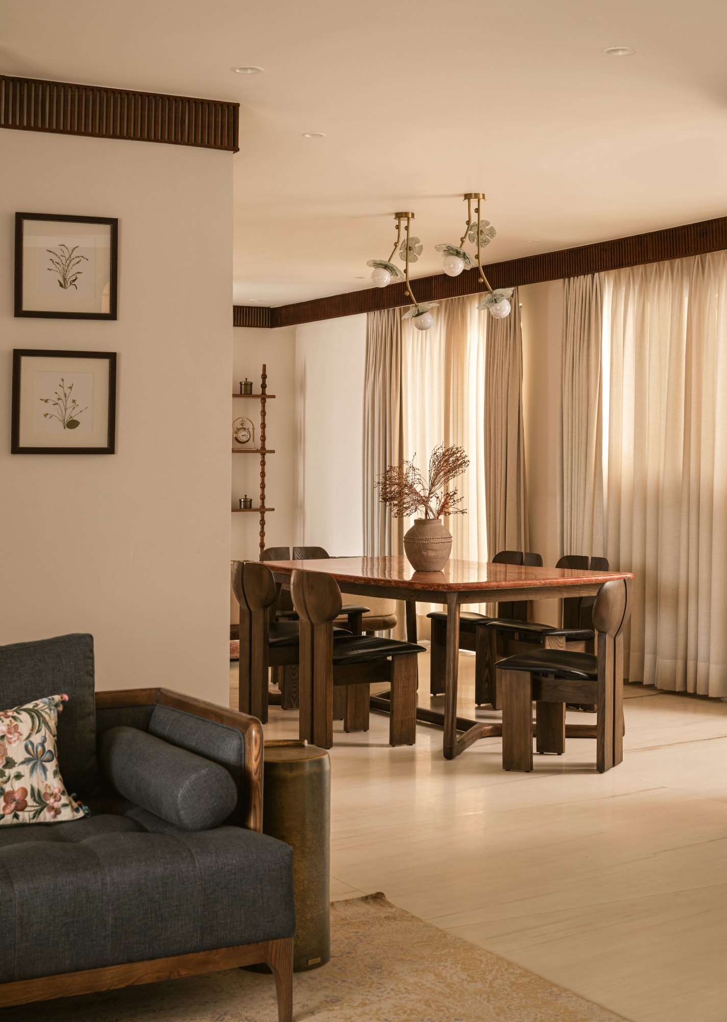 Dining table in red stone with sculptural wooden chairs and a glass leaf chandelier