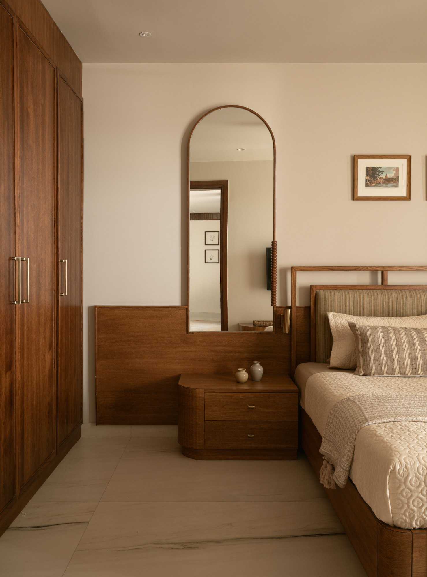 Teak bedroom with arched mirror, fitted wardrobes and bedside joinery