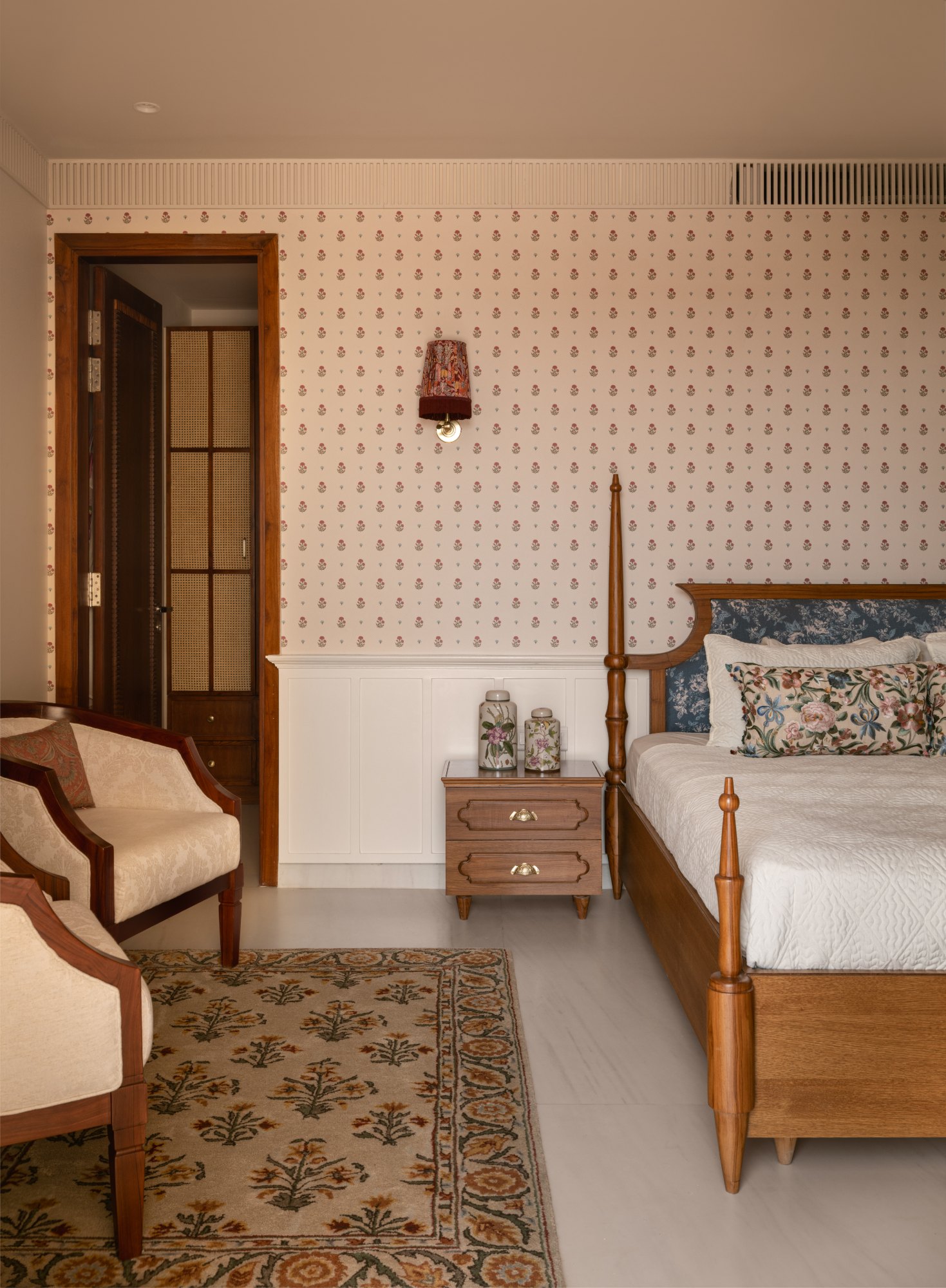 Guest bedroom with block-print floral wallpaper, white panelling and a four-poster bed