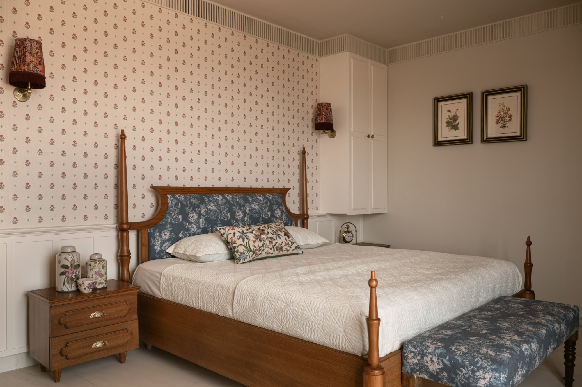 Guest bedroom seen wide, with four-poster bed, floral bench and Kashmiri rug