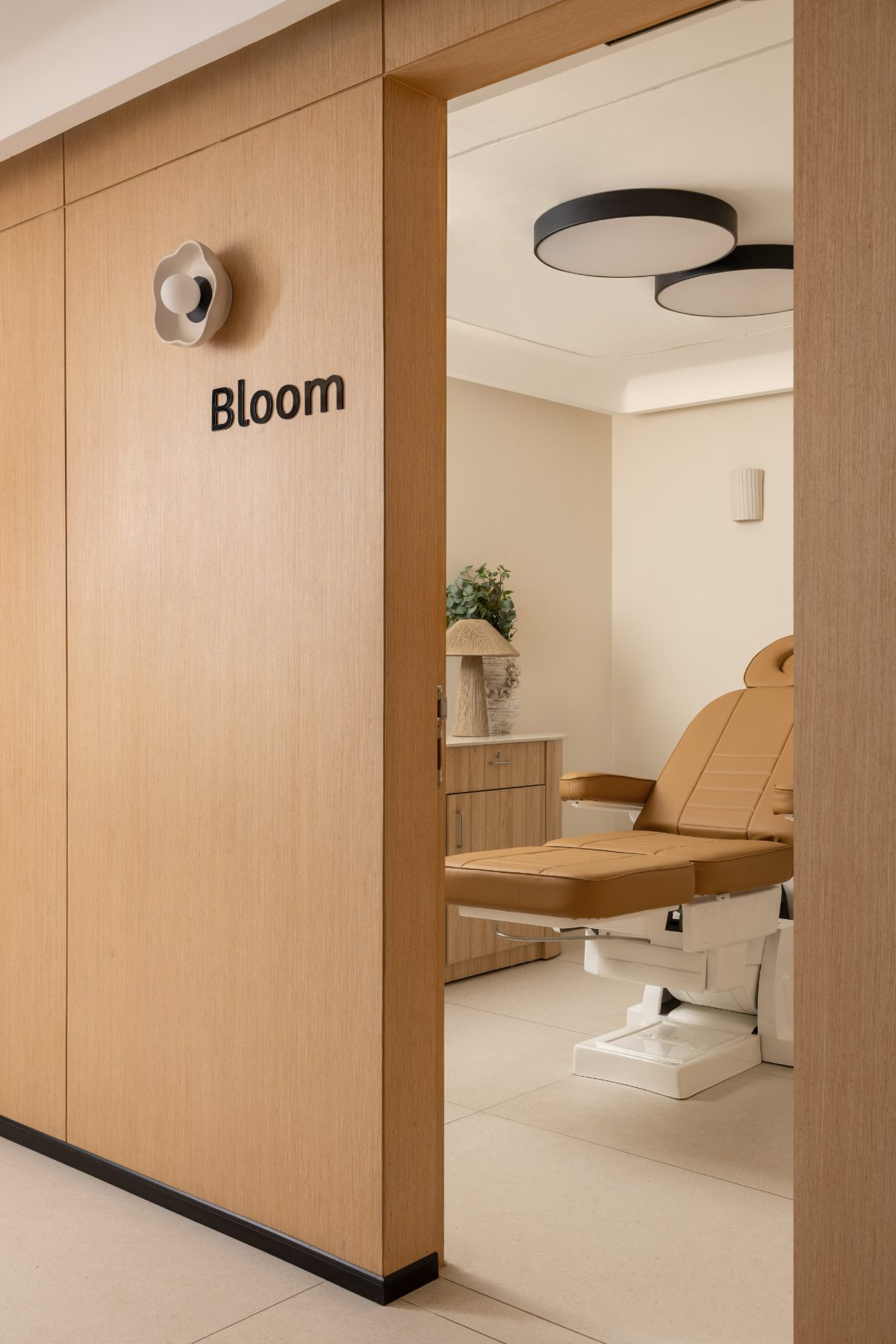 Bloom treatment room with a facial bed seen through oak doors