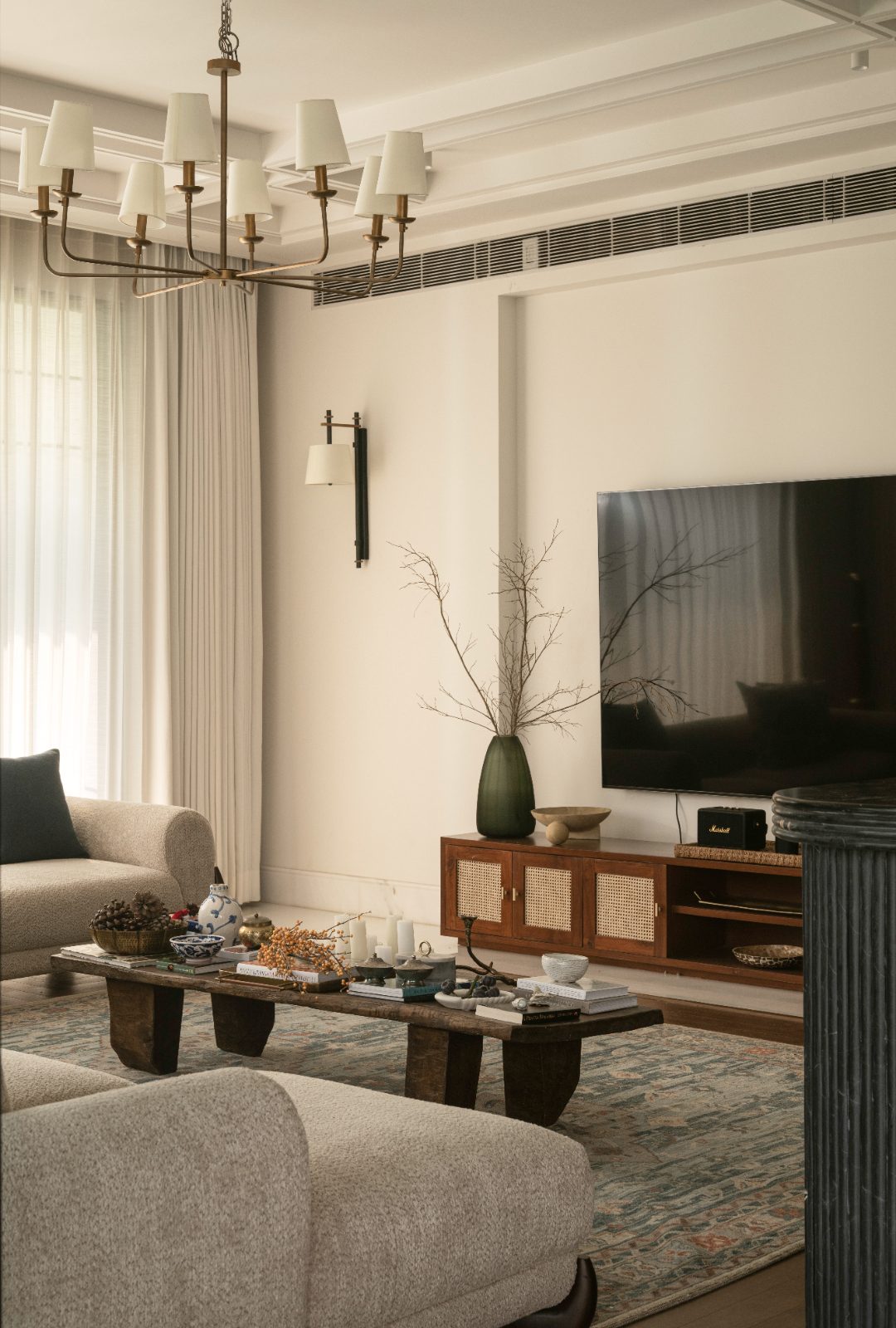 Living room with brass chandelier, bouclé seating and cane console