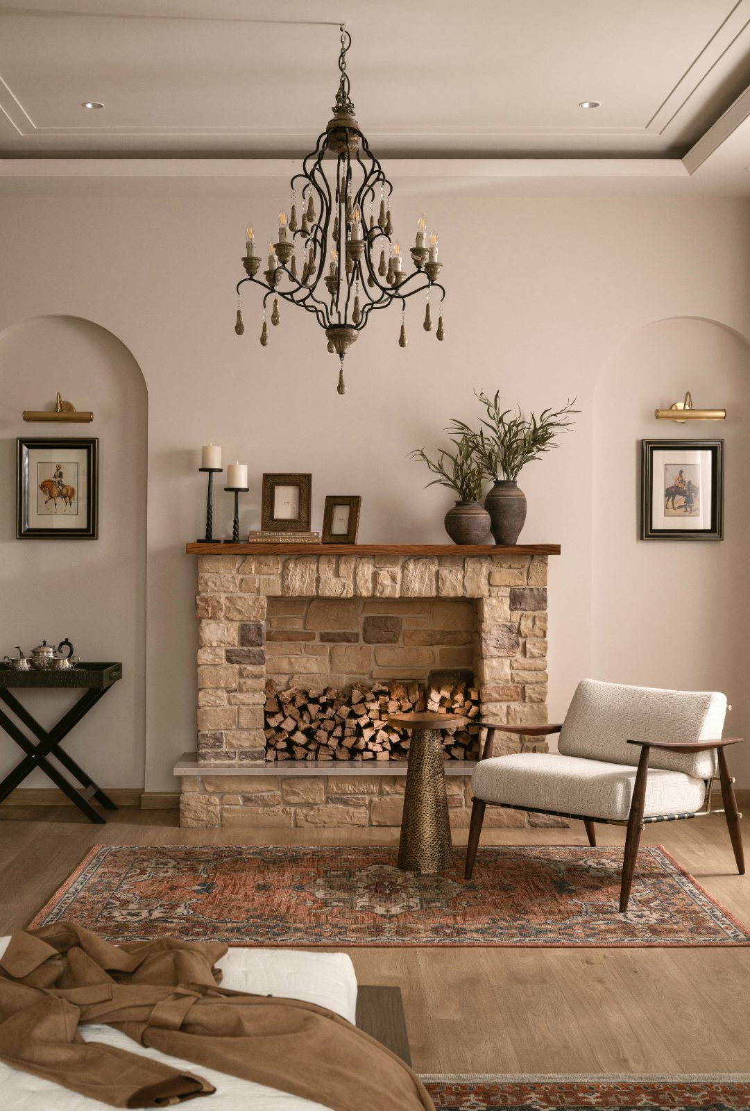 Sitting room with a rustic stone fireplace, iron chandelier and cane chair