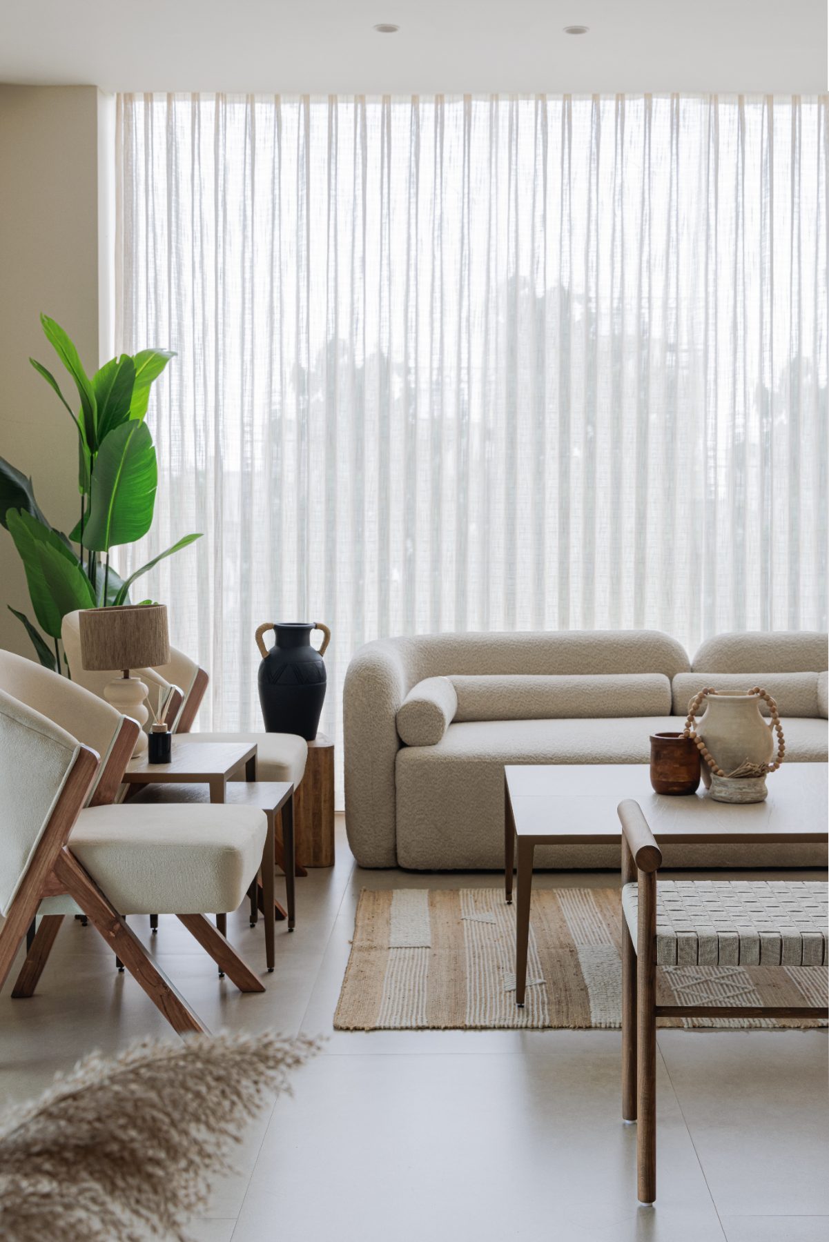 Waiting lounge with linen sofa, cane chairs and sheer-draped window