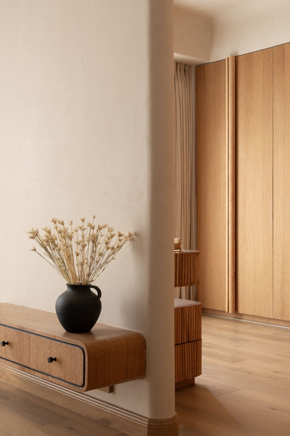 Floating oak console with a black vase of dried flowers