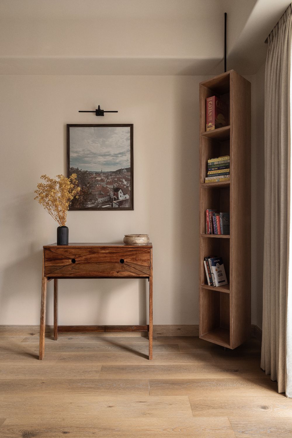 Console with framed print and a tall timber bookshelf
