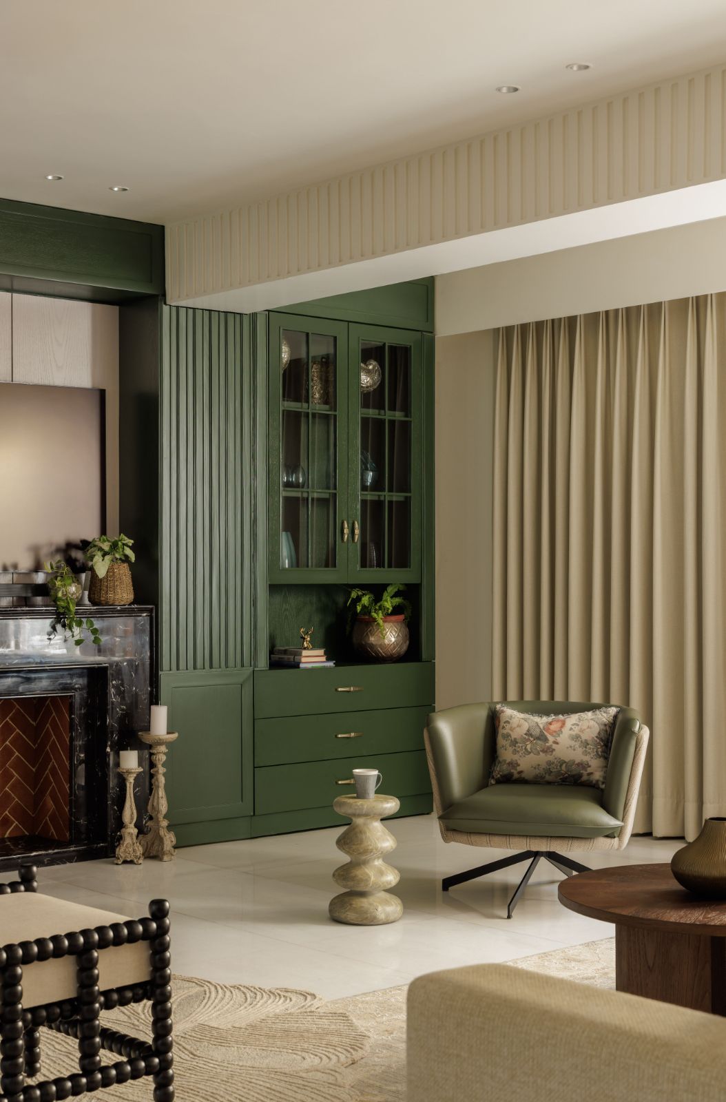 Green-lacquered fluted cabinet beside a black marble fireplace
